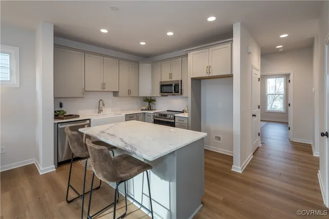 a kitchen with stainless steel appliances granite countertop a refrigerator a sink dishwasher a stove and white cabinets with wooden floor