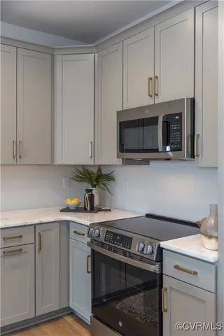 a kitchen with stainless steel appliances granite countertop grey cabinets a stove a sink and dishwasher