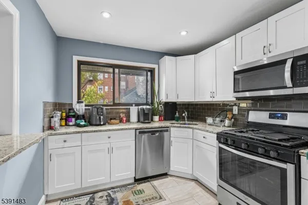 a kitchen with granite countertop a sink a stove a microwave and cabinets