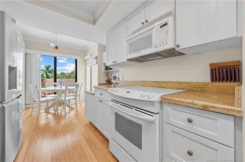 a kitchen with granite countertop white cabinets and white appliances