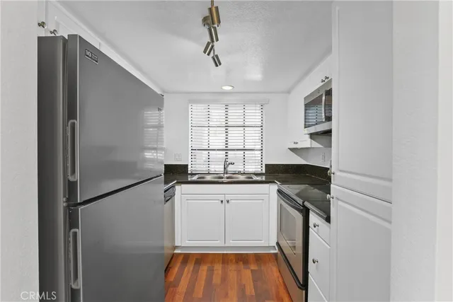 a kitchen with granite countertop stainless steel appliances a sink stove and cabinets