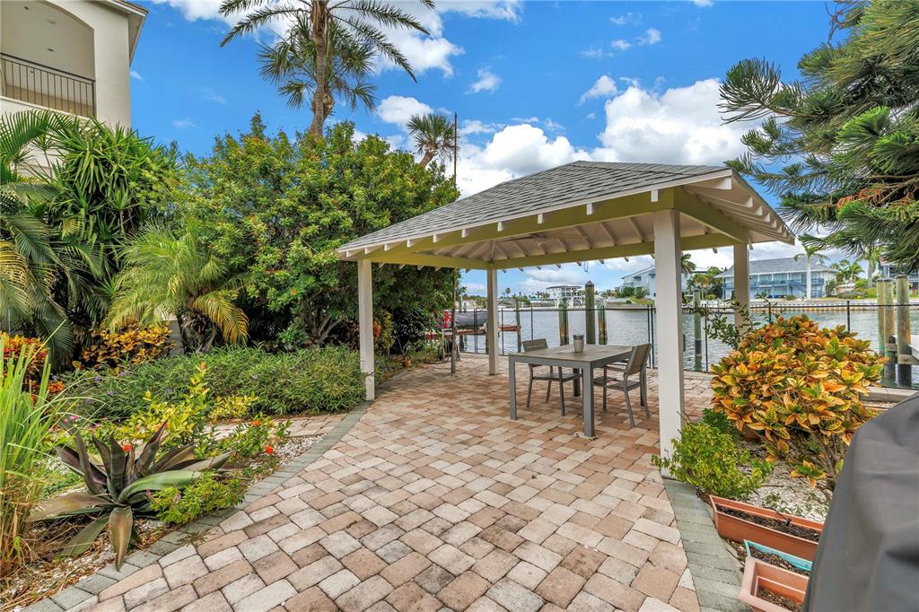 2605 Pass A Grille Way St. Pete Beach, FL 33706 - Photo 30 of 41 a view of a patio with table and chairs under an umbrella with potted plants