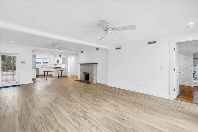 a large white kitchen with stainless steel appliances granite countertop a stove a sink a refrigerator and white cabinets with wooden floor