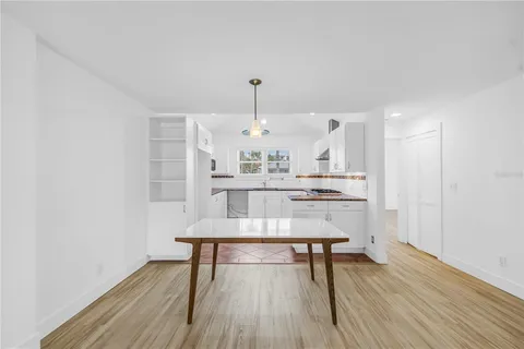 a large white kitchen with stainless steel appliances granite countertop a stove a sink a refrigerator and white cabinets with wooden floor