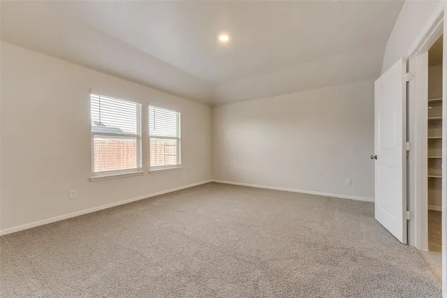 an empty room with a window and a kitchen