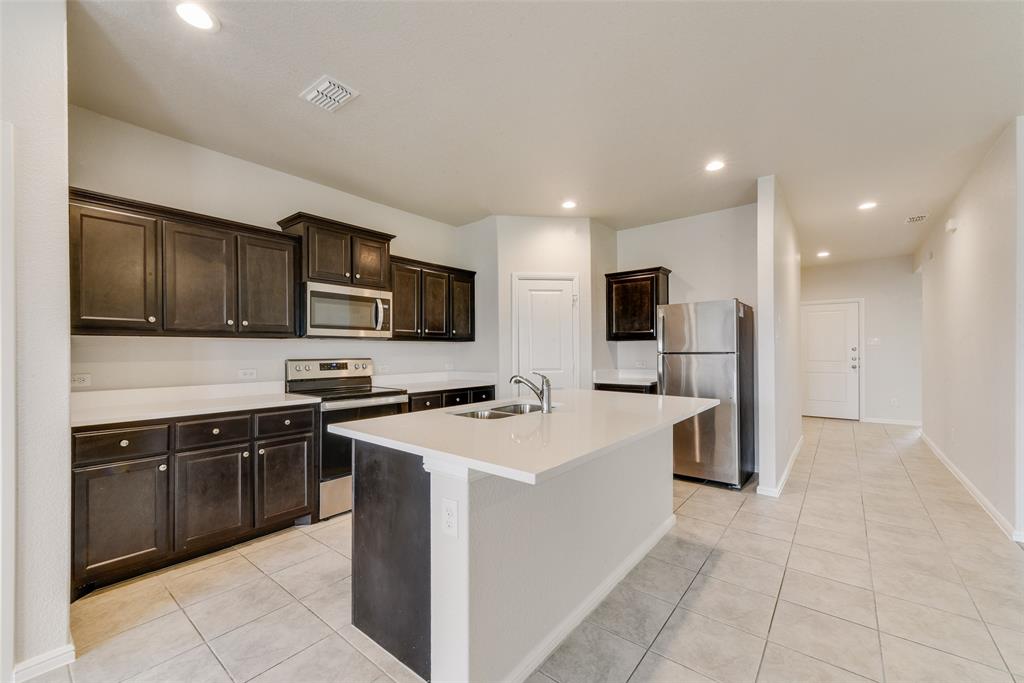 711 Durango Lane Cleburne, TX 76033 - Photo 9 of 26 a kitchen with stainless steel appliances a stove sink microwave and cabinets