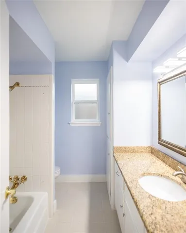 a bathroom with a granite countertop sink and a bathtub