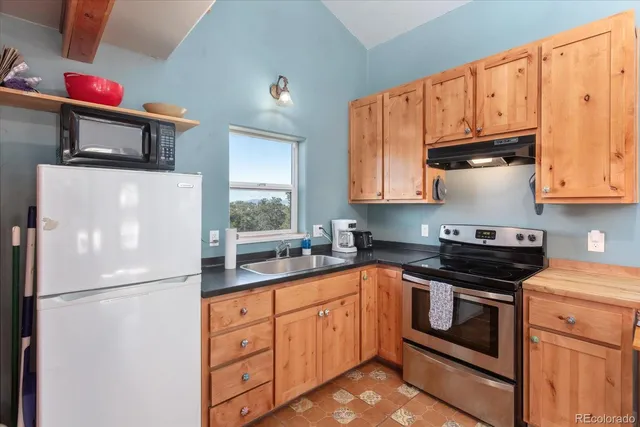 a white kitchen with granite countertop stainless steel appliances and wooden cabinets