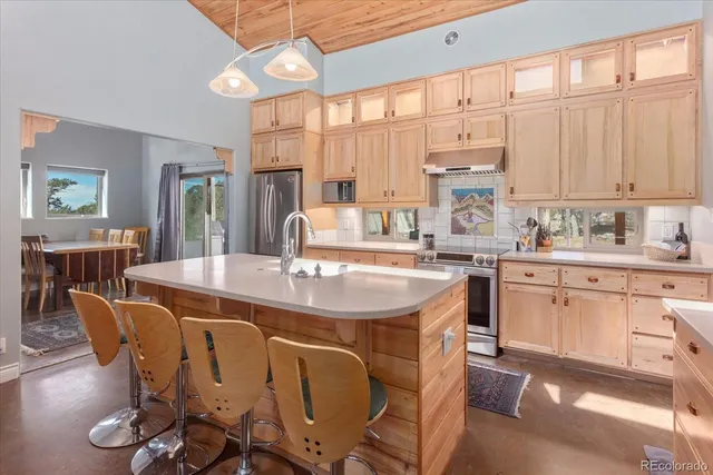 a kitchen with stainless steel appliances a table chairs and a large window