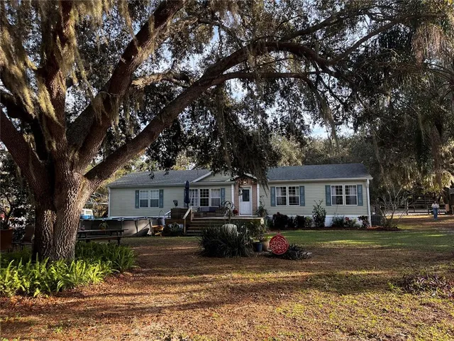 a front view of a house with a garden and trees