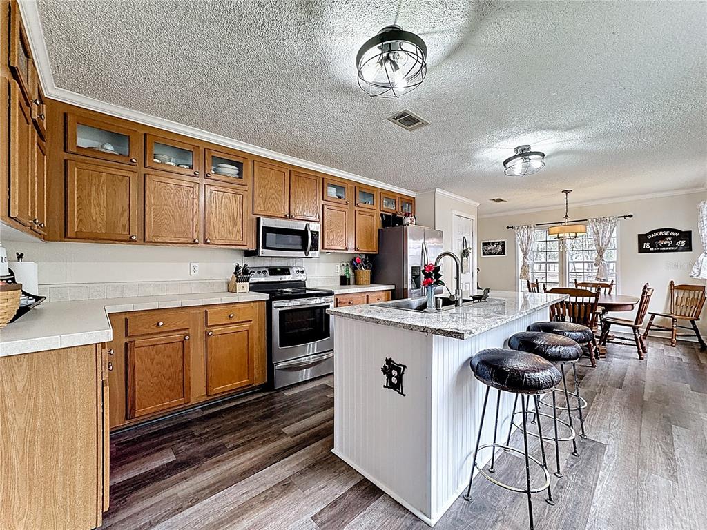 3230 Empire Church Road Groveland, FL 34736 - Photo 4 of 29 a kitchen with a refrigerator a stove cabinets and living room view