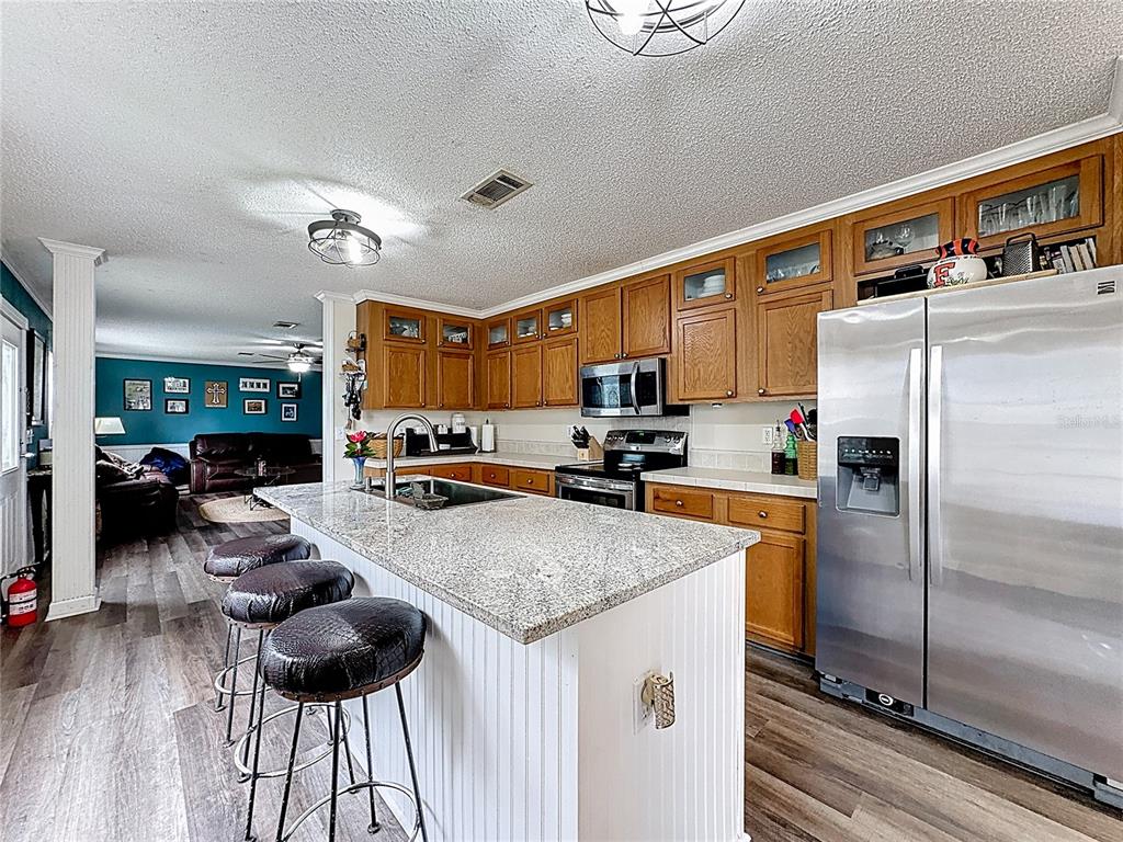 3230 Empire Church Road Groveland, FL 34736 - Photo 5 of 29 a kitchen with stainless steel appliances granite countertop a refrigerator a stove and a sink with wooden floor