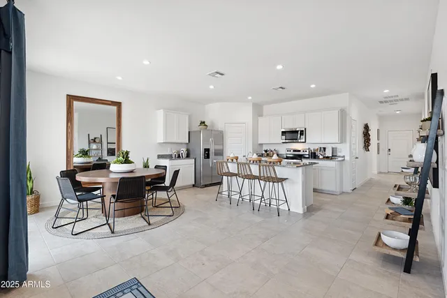 a room with stainless steel appliances kitchen island granite countertop furniture and a dining table