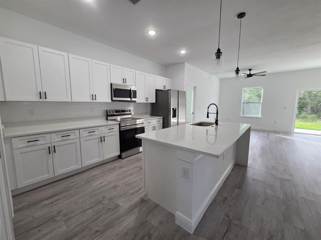 4863 Southwest 159th Lane Ocala, FL 34473 - Photo 5 of 16 a kitchen with cabinets stainless steel appliances a sink and a center island
