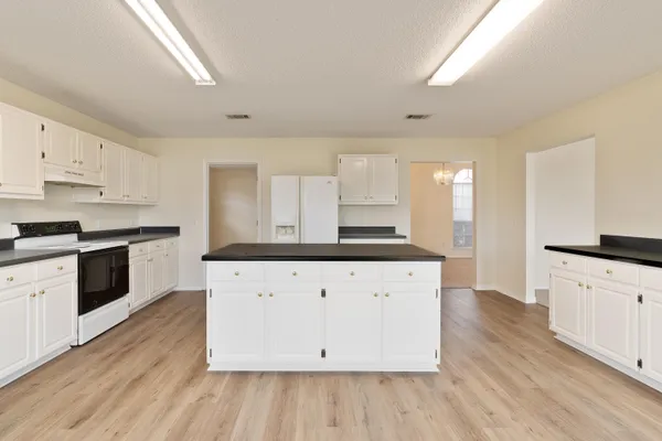 a large white kitchen with granite countertop white cabinets and white appliances