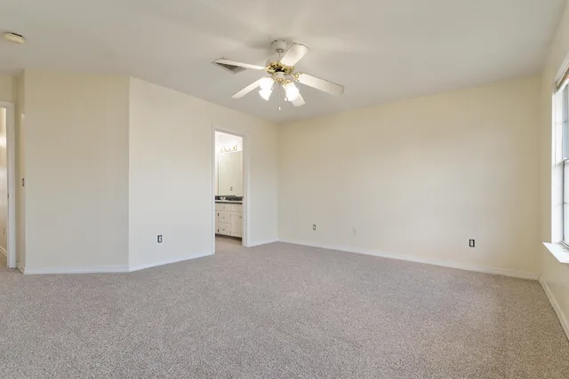 a view of an empty room with a ceiling fan and window