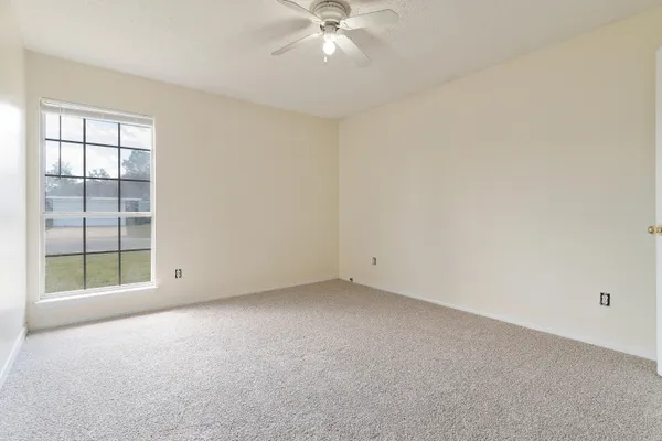 an empty room with a window and a fan