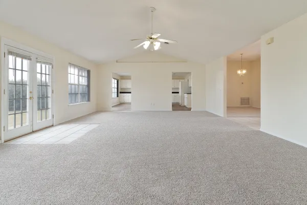 a view of a big room with windows and chandelier fan
