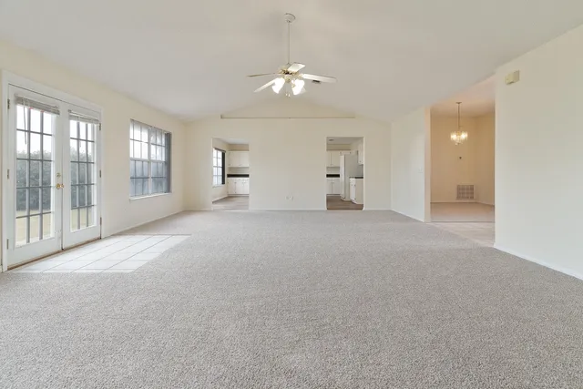 a view of a big room with windows and chandelier fan