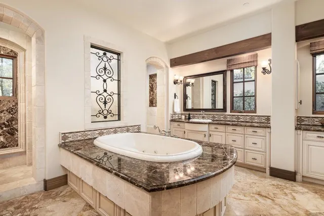a bathroom with a granite countertop tub a sink and a large mirror