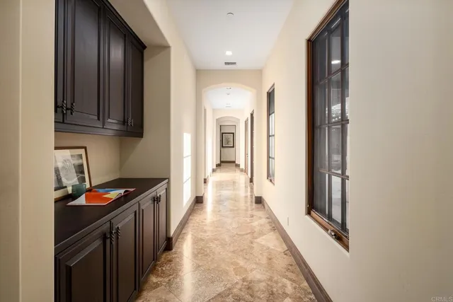 a hallway with white cabinets and black appliances