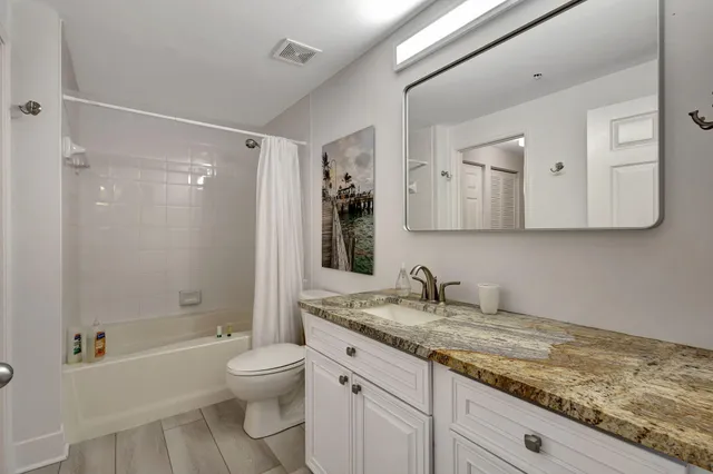 a bathroom with a granite countertop sink toilet and shower
