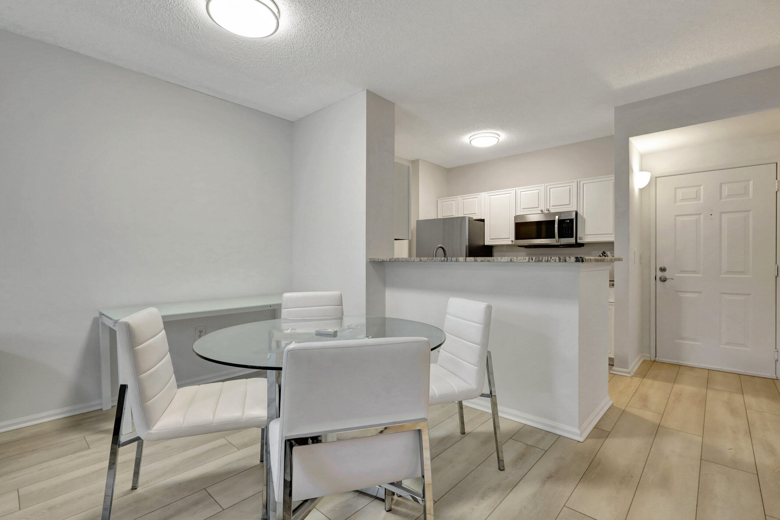 630 South Sapodilla Avenue, Unit 223 West Palm Beach, FL 33401 - Photo 8 of 43 a kitchen with kitchen island granite countertop a dining table chairs refrigerator and cabinets