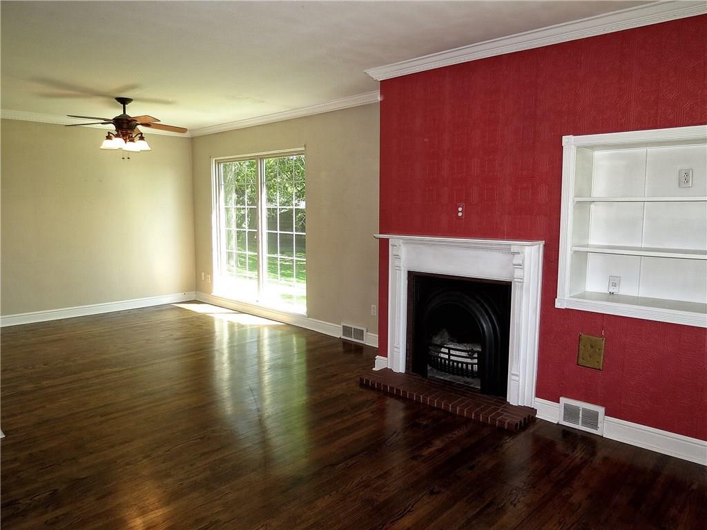 A large floor to ceiling window lends style and sunlight to the living room while the fireplace, hardwood floors, crown molding & built in book case lend warmth & charm.