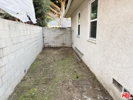 a view of a pathway of a house with backyard and wooden fence