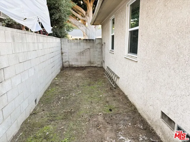 a view of a pathway of a house with backyard and wooden fence