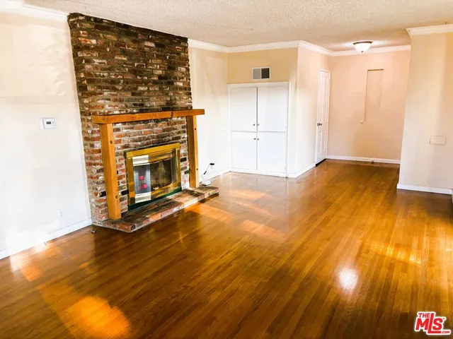a view of a livingroom with wooden floor and a fireplace
