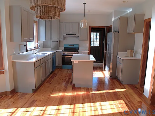 a kitchen with stainless steel appliances granite countertop a refrigerator a sink dishwasher a stove and white countertops with wooden floor