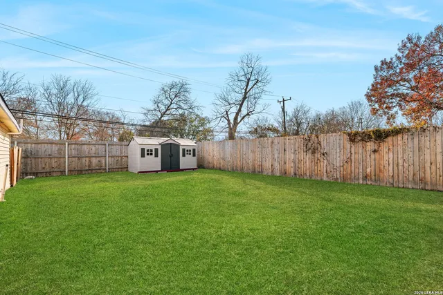 a view of a backyard with large trees and wooden fence