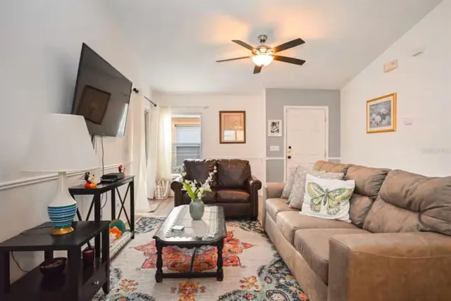 a living room with furniture a ceiling fan and a flat screen tv