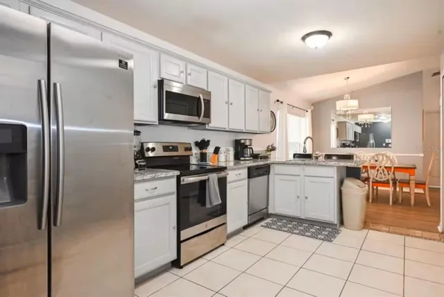 a kitchen with granite countertop a refrigerator and a stove top oven