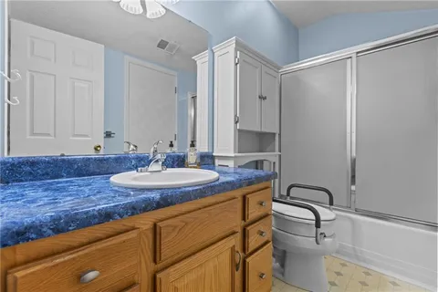 a bathroom with a granite countertop sink a toilet and a mirror