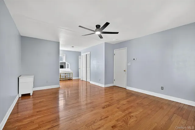 a view of an empty room with window and wooden floor