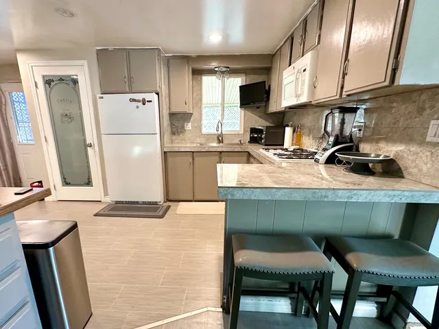 a kitchen with a sink a refrigerator a stove a microwave oven and a dining table with wooden floor