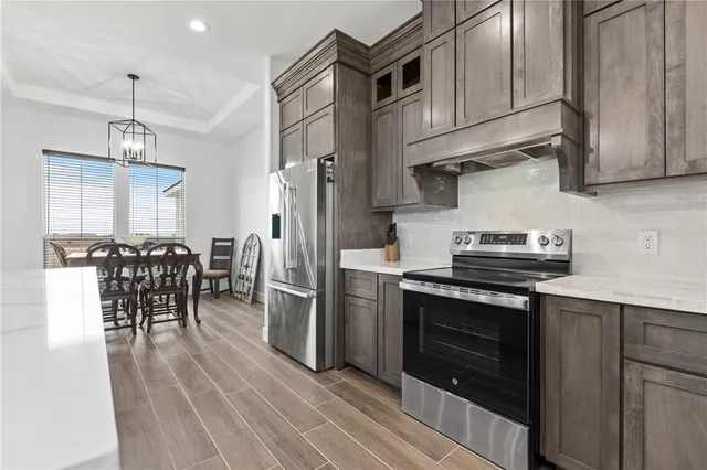 a kitchen with stainless steel appliances granite countertop a stove a refrigerator and a wooden floors