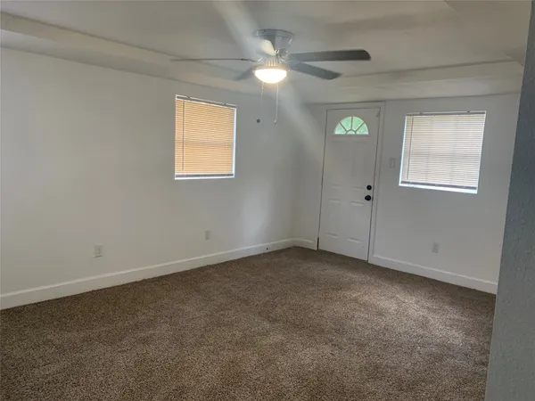 an empty room with windows and fan