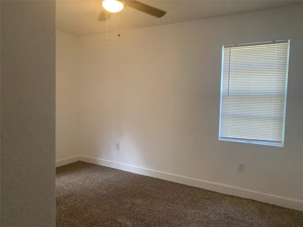 an empty room with a fan & a window
