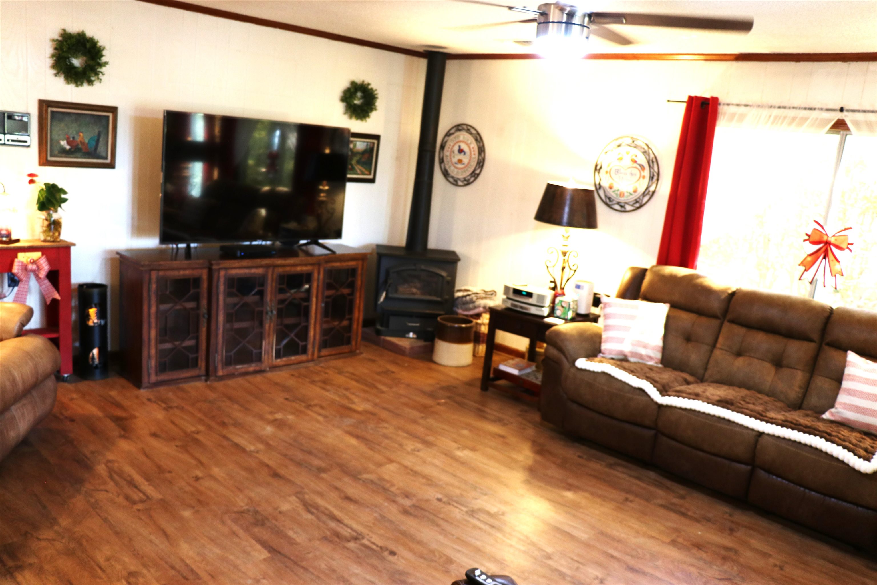 937 Kelleys Chapel Road Burlison, TN 38015 - Photo 8 of 27 Living area featuring wood finished floors, ornamental molding, a wood stove, and ceiling fan
