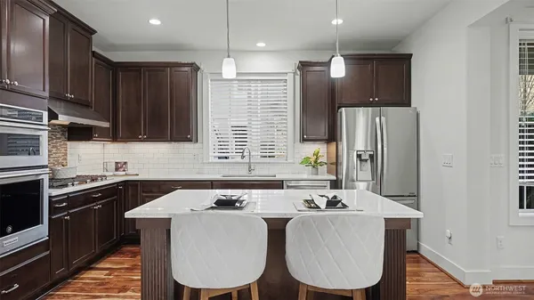 a kitchen with stainless steel appliances granite countertop a sink a stove a refrigerator cabinets and a dining table