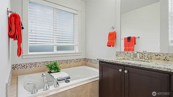 a bathroom with a granite countertop sink and a bathtub
