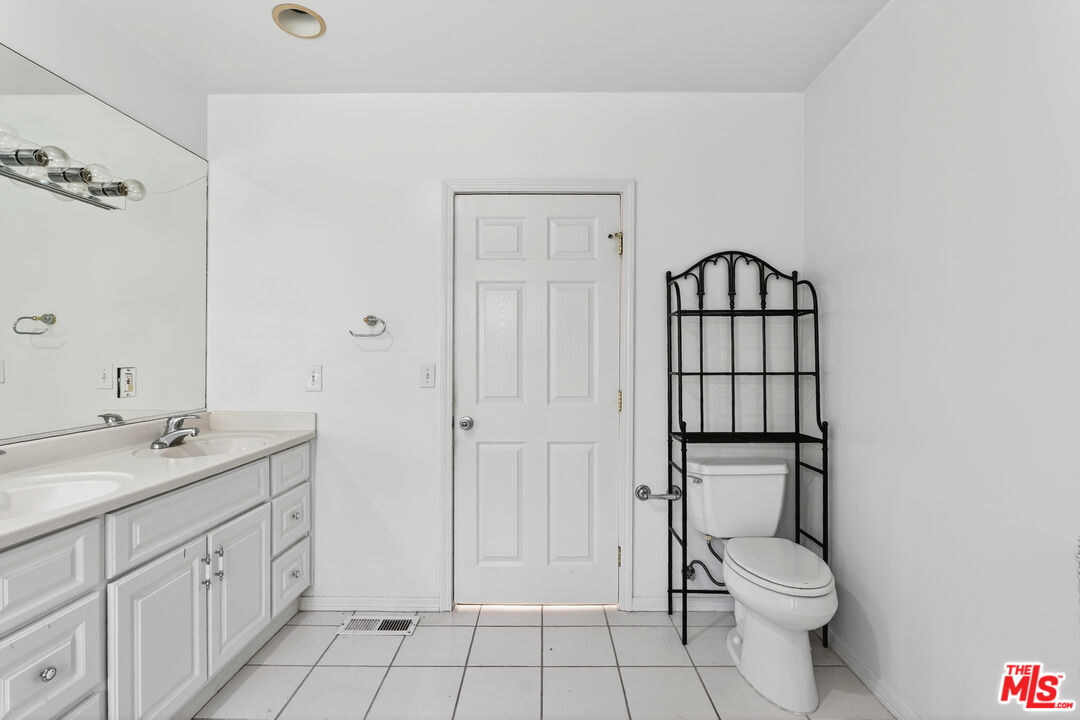 1544 South Point View Street Los Angeles, CA 90035 - Photo 44 of 67 a bathroom with a granite countertop toilet a sink and a mirror