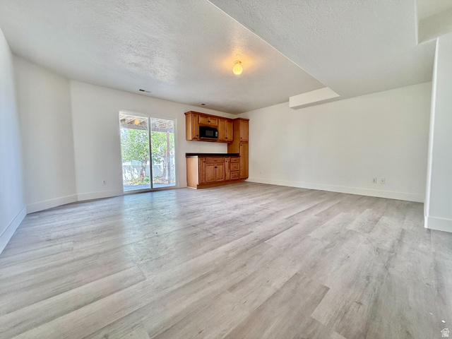1705 80 East Tooele, UT 84074 - Photo 16 of 22 Spacious room featuring light wood-finish flooring, white walls, and a built-in kitchenette