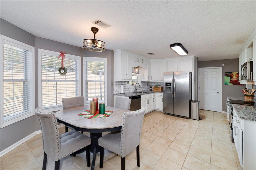 121 Harper Road McDonough, GA 30252 - Photo 17 of 38 a kitchen with stainless steel appliances kitchen island granite countertop a refrigerator a stove a microwave oven a dining table and chairs with wooden floor