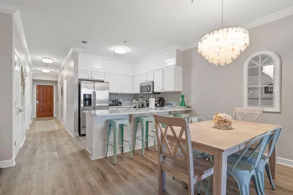 a kitchen with stainless steel appliances granite countertop a dining table chairs and a refrigerator