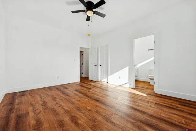 a view of empty room with wooden floor and ceiling fan