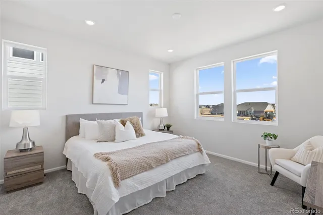 a bedroom with a bed a painting on the wall and a window